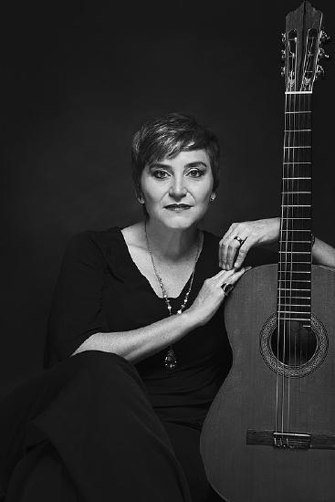 A woman sitting with an acoustic guitar
