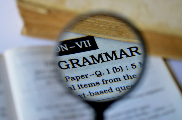 magnifying glass held over the word "grammar" in a dictionary