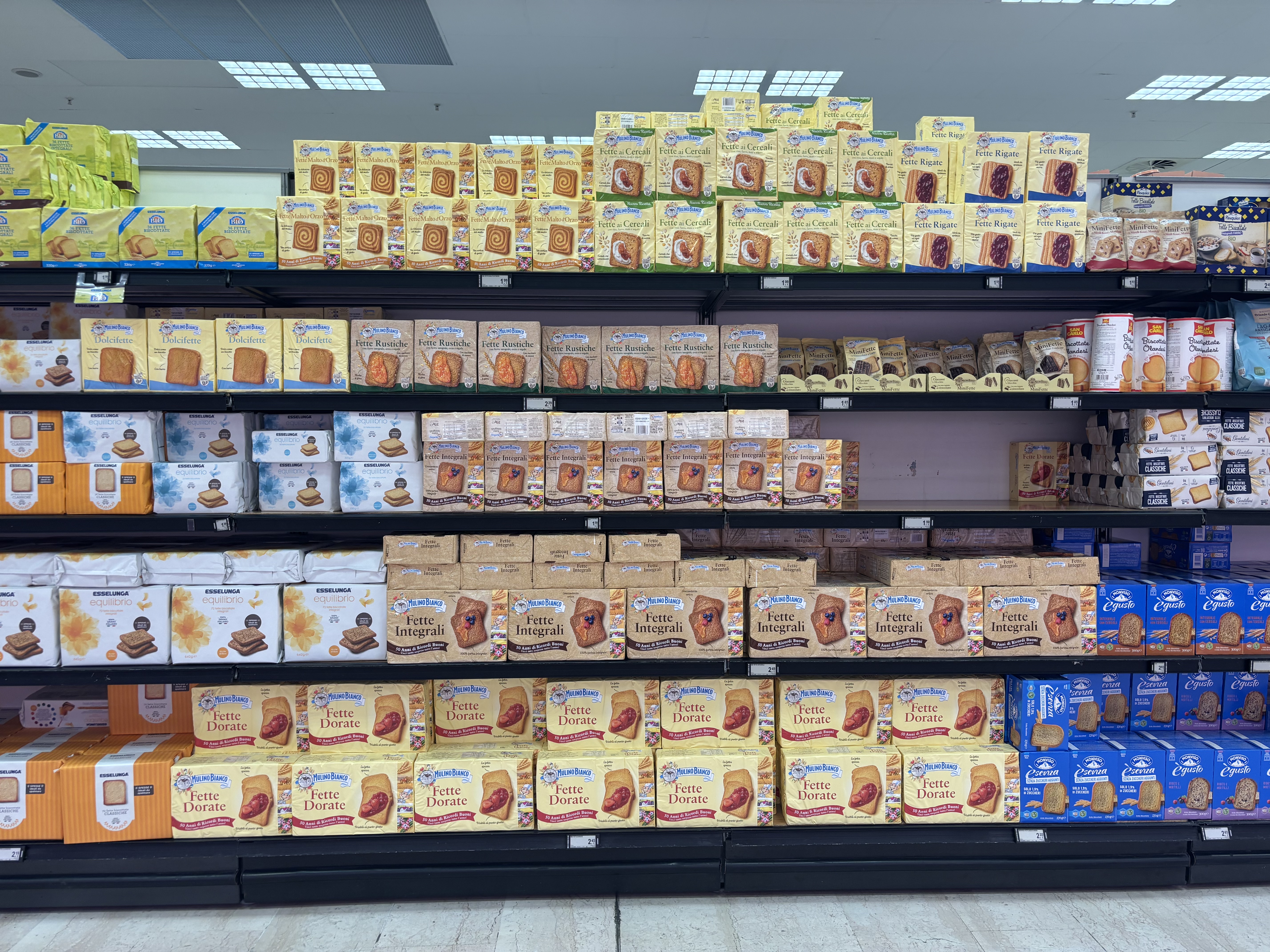 A grocery store shelf displaying various brands of cookies and snacks, organized in boxes with colorful packaging.