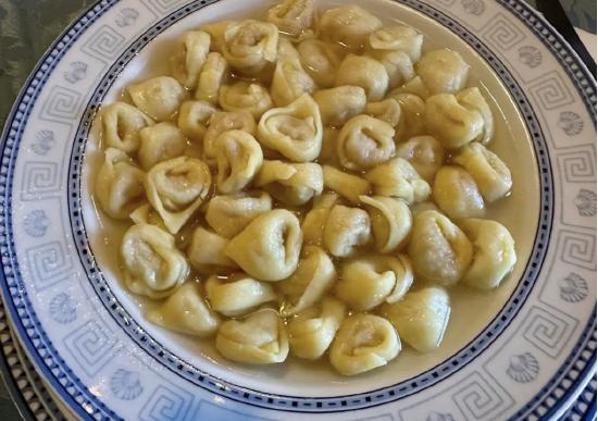 A plate of dumplings in broth, featuring small, folded, and slightly translucent dough pieces.