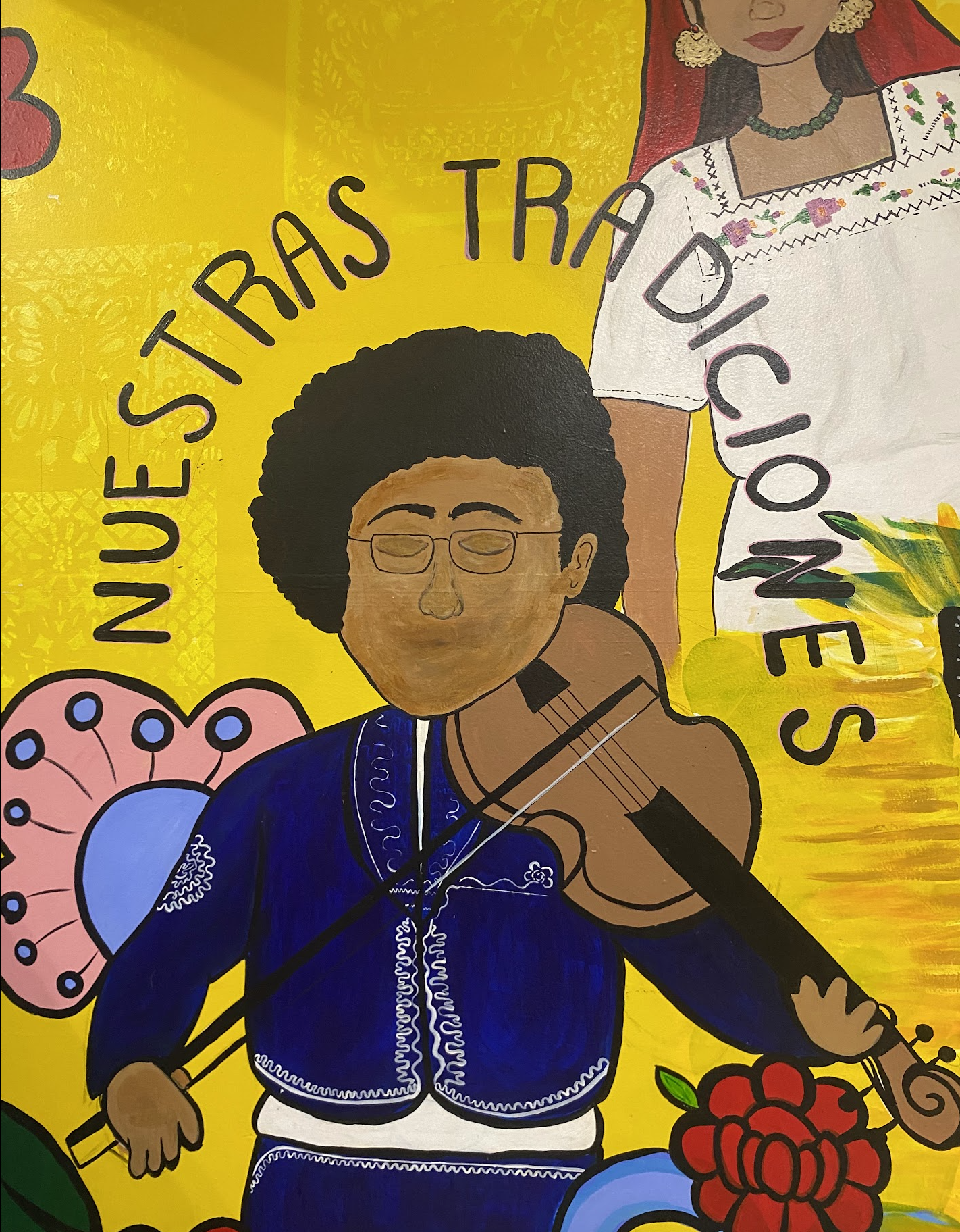 mural con una mujer tocando el violin con el texto que dice "Nuestras Tradiciones". 