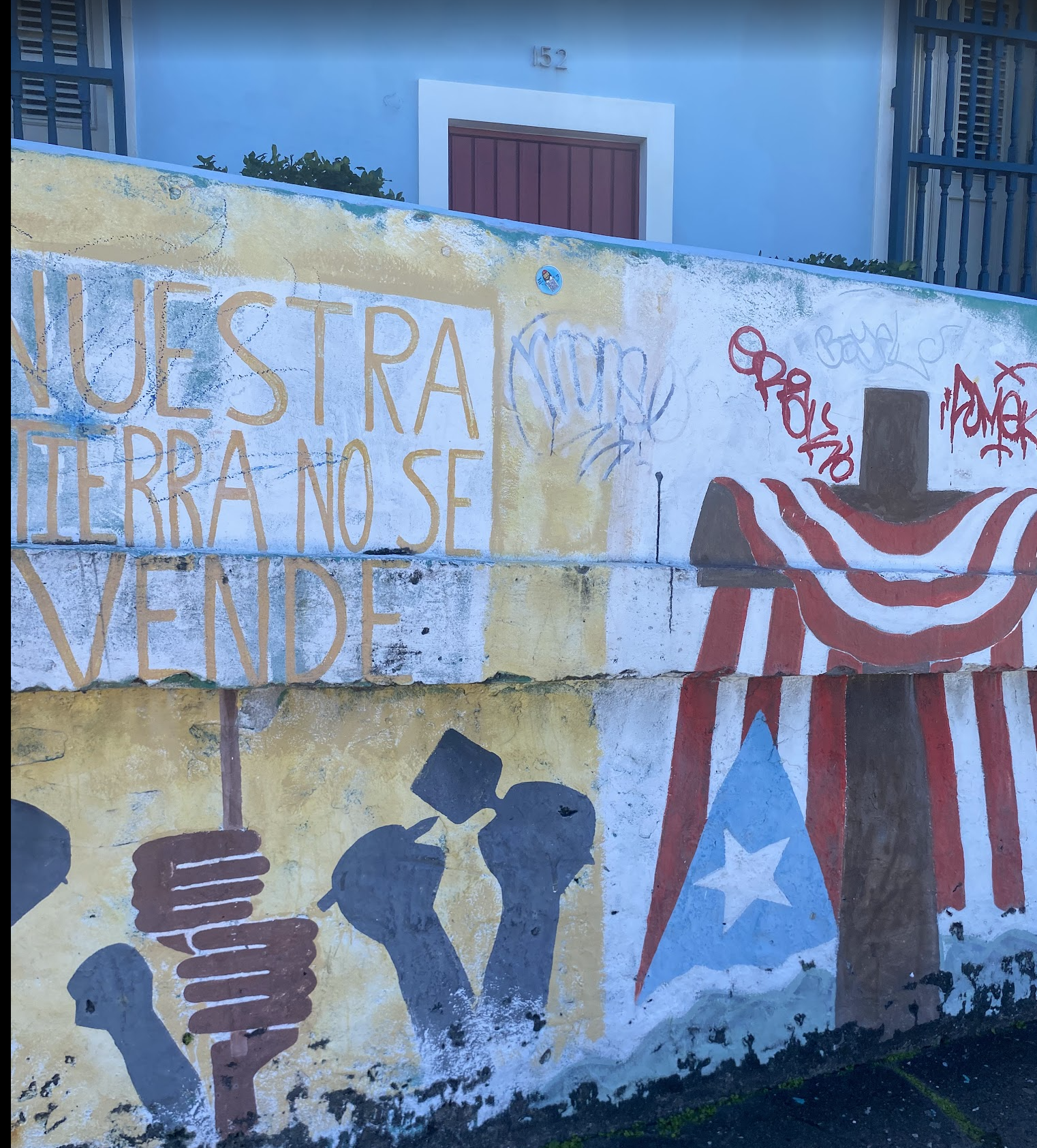 imagen de mural en Puerto Rico con pu&ntilde;os y una bandera y el texto "Nuestra tierra no se vende"