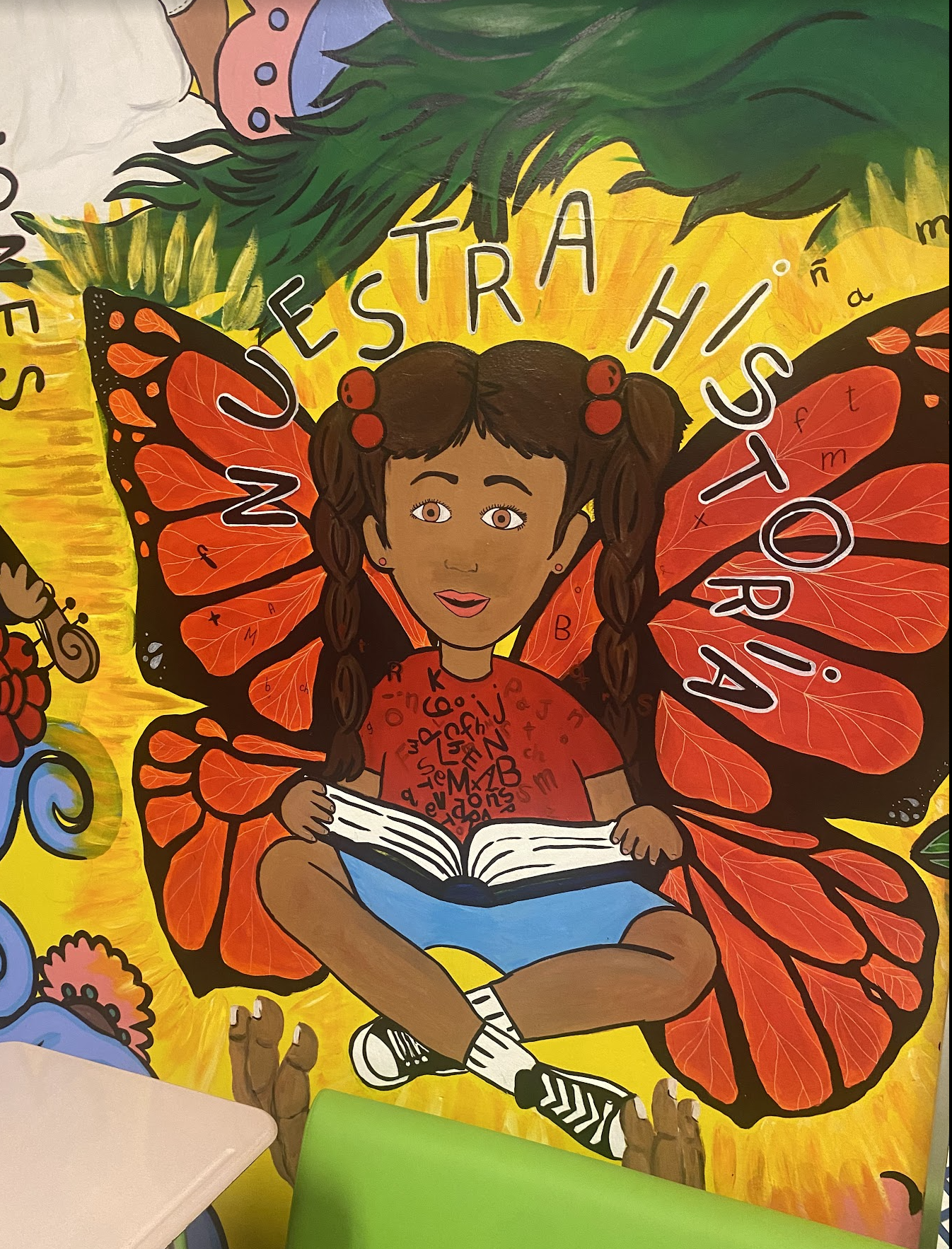 Mural de una ni&ntilde;a sentada con un libro con alas de una mariposa monarca