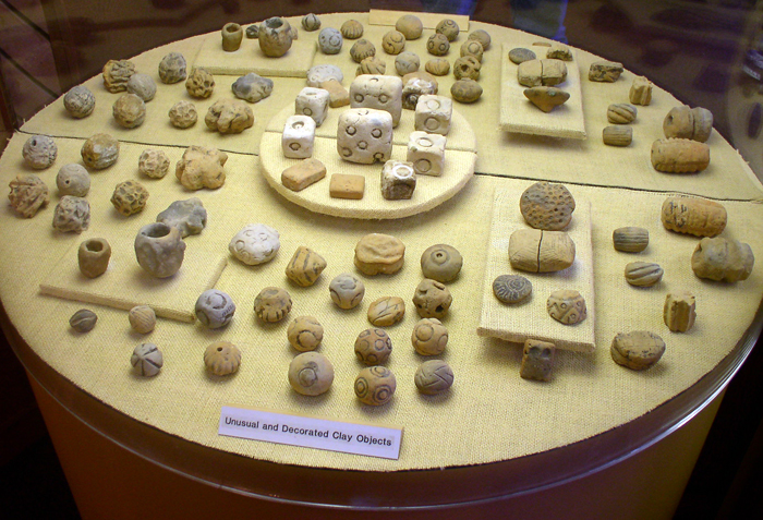 These small decorative clay objects are representative of the earliest artifacts discovered from Poverty Point, Louisiana. Spherical or geometric in shape, these clay fired objects are thought to have been used as artificial cooking stones. 