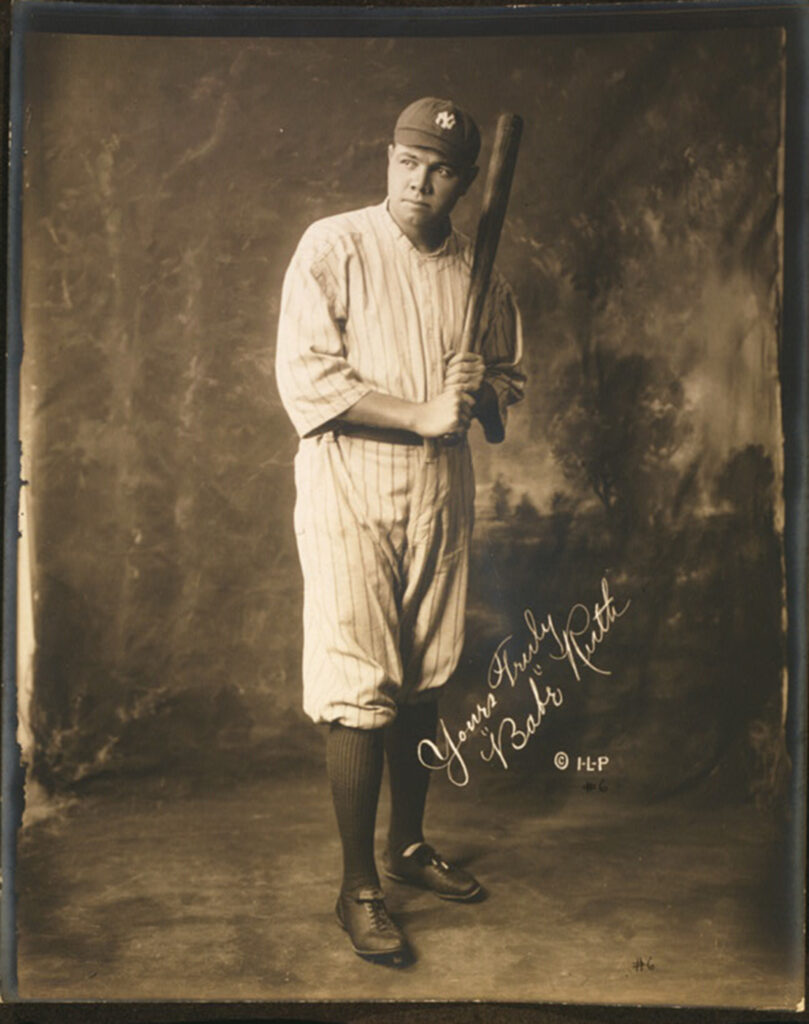 A man in a baseball uniform poses with a bat.