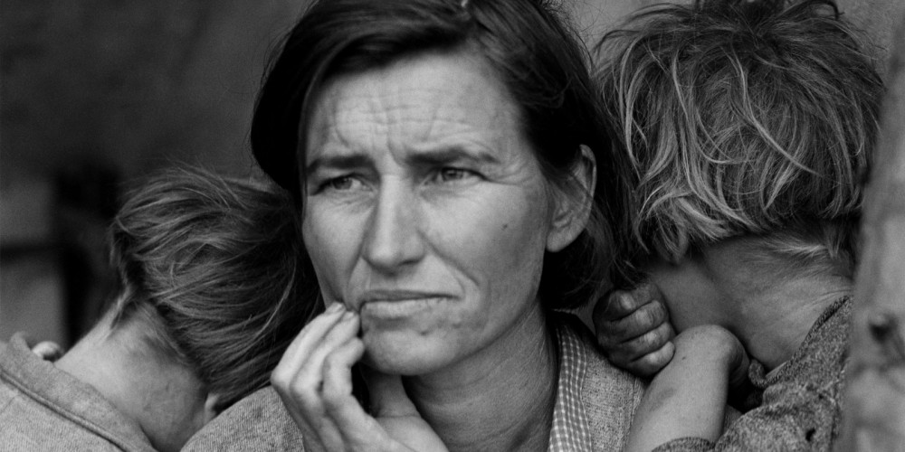 A woman looks worriedly into the distance, as two children rest against her shoulders.