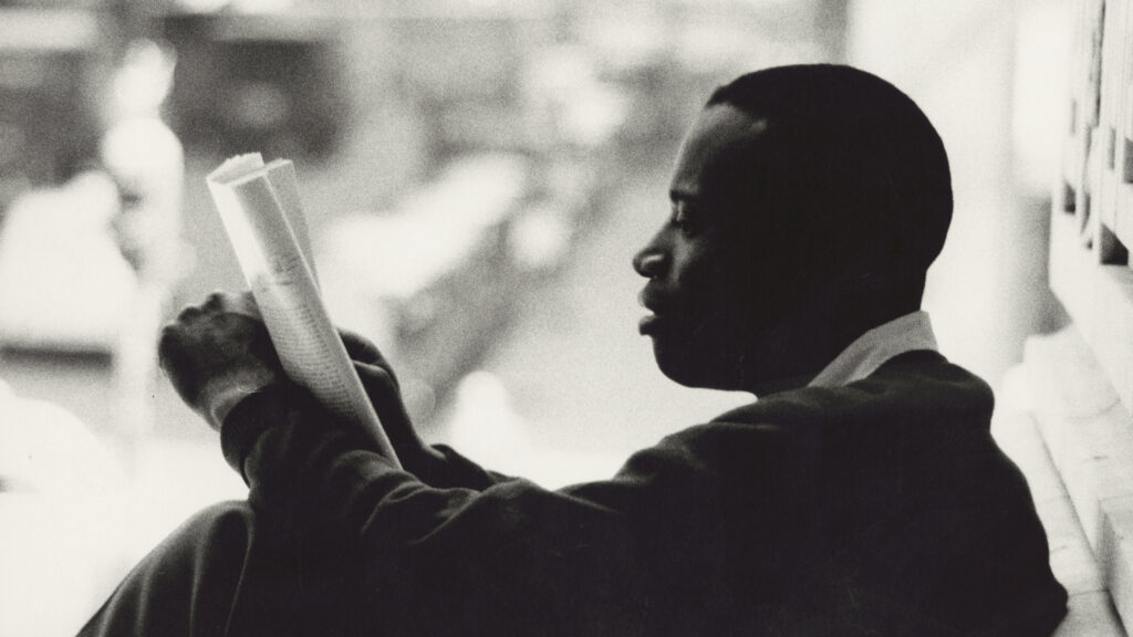 A young man reads a newspaper.