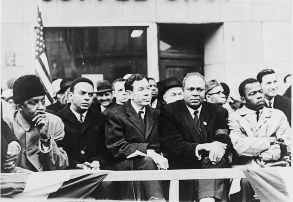 Five men sit at a rally.