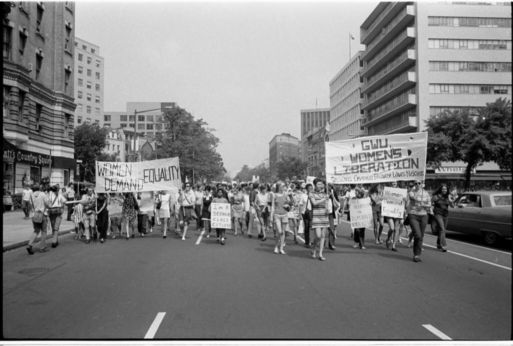 Women march down a city street with large banners reading &ldquo;Women Demand Equality&rdquo; and &ldquo;GWU Women&rsquo;s Liberation.&rdquo; 