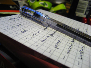Foto de una lista escrita a mano sobre papel gráfico, con un bolígrafo en la parte superior