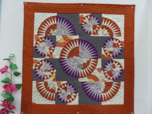 Square quilt with circles of orange, purple, gray, and white