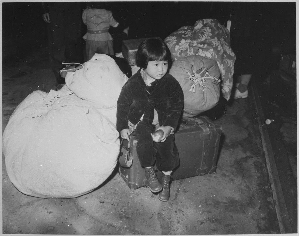 A_young_evacuee_of_Japanese_ancestry_waits_with_the_family_baggage_before_leaving_by_bus_for_an_assembly_center..._-_NARA_-_539959-1024x808.jpg