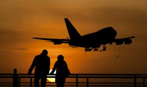 Two people and an airplane silhouetted against a sunset