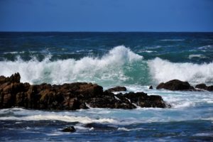 Photo of waves crashing against rocks.