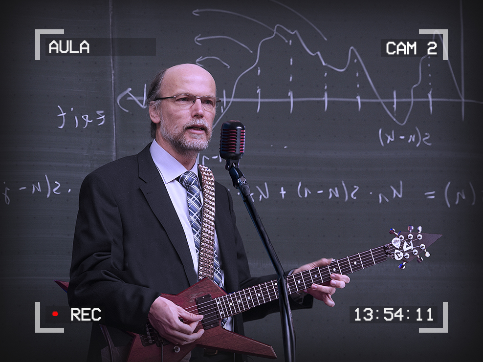 Image of a man in a suit in front of a blackboard playing electric guitar with a microphone in front of him. Text around the outside of the image reads: Aula, Cam 2, 13:54:11, Recording