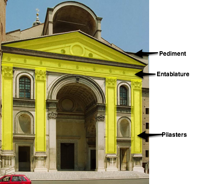 La fachada con formas específicas resaltadas. Hay pilastras (dos a cada lado de la puerta), un entablamiento por encima de éstas, y un frontón encima del entablamiento.