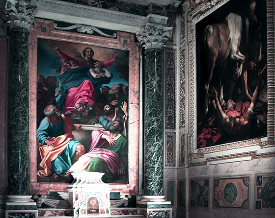 Dos pinturas se muestran en esta fotografía de la capilla. Cada cuadro tiene un marco intrincadamente tallado. La Asunción también está flanqueada con columnas corintias talladas en mármol.