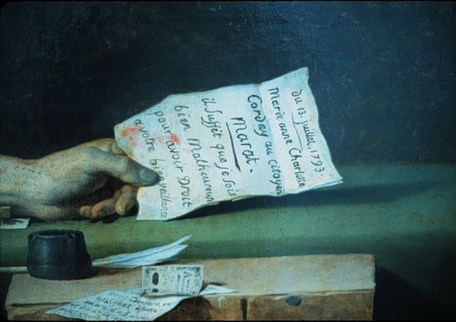 La mano de Marat sosteniendo la carta. Hay sangre en la carta, que se puede leer claramente.