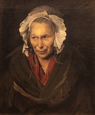 Una anciana vestida con un capó blanco. Lleva un manto marrón sobre ropa roja. Sus ojos miran a un lado, enfocados en algo que la vista no puede saber.
