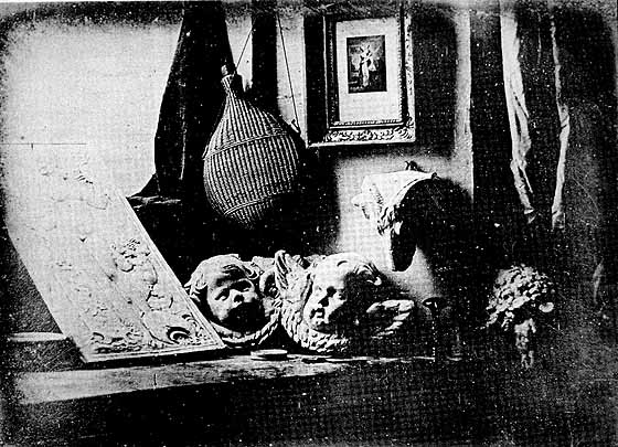 a black and white daguerreotype featuring a window, two sculpted cupid heads, a flask, and a painting.