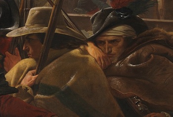 Dos hombres agachados en el bote, uno sosteniendo un rifle, el otro con la cabeza vendada.