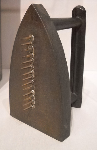 An iron with a straight row of fourteen tacks welded to the center of its bottom