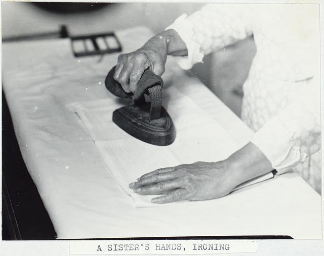 A woman using an iron on clothing.