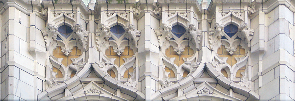 The face of the building is primarily white, with intricate swoops, curls, and fleur de lis. These swooping carvings expose blue and yellow beneath them.