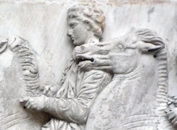 Close up photograph of the high-relief frieze of the Parthenon. This portion features a man on a war horse.