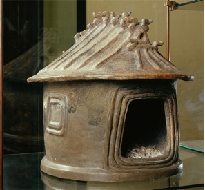The urn has a large opening in the front and the top is shaped like a roof .