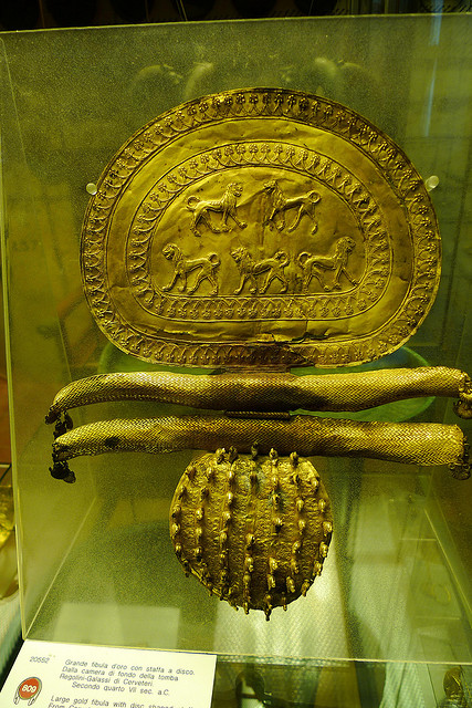 Pieza de joyería de oro adornada; Hay intrincadas tallas en la parte superior que representan animales carnívoros