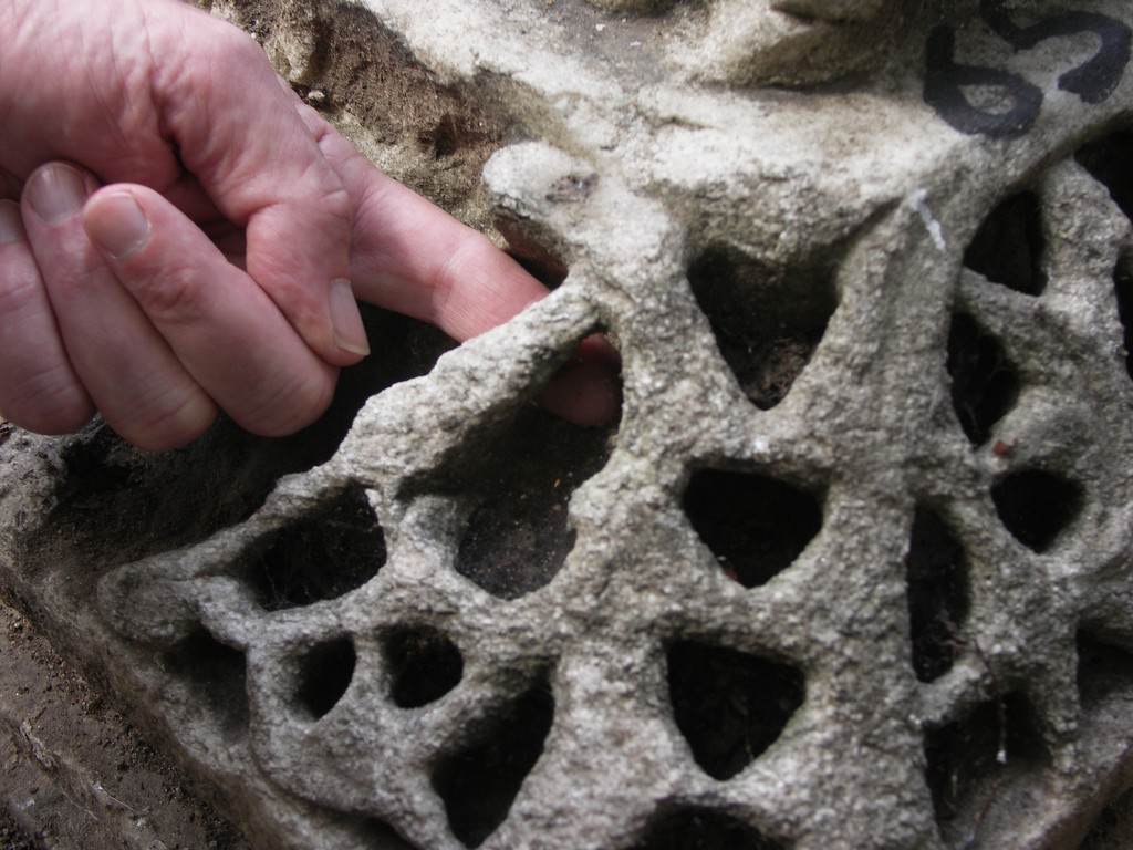 A basket capital fragment; the photographer is sticking a finger from their other hand behind the carvings to show that the capital is, indeed, hollow.