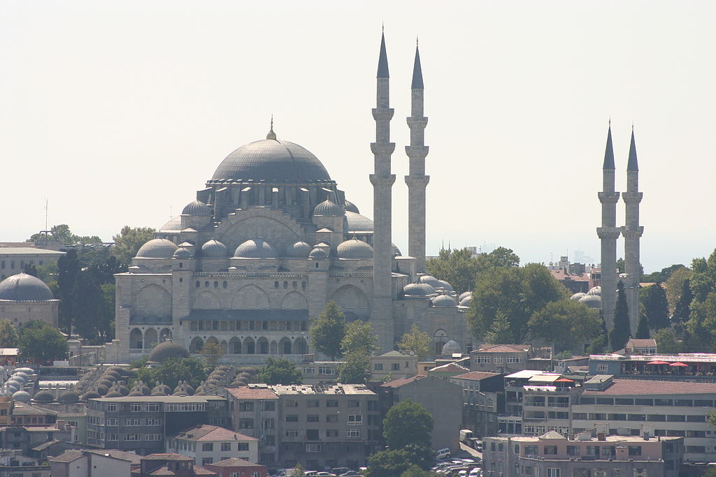 Mosque with the typical center dome and other surrounding domes. The minarets instead of forming a square around the mosque form a sort of rectangle to its side. The two minarets immediately next to the mosque are taller than the other two.