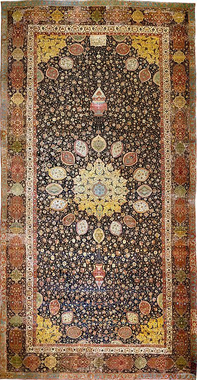 Intricate carpet with radial symmetry. The carpet is rectangular and the central radial pattern is framed by a border along the edges.