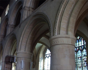 Interior walkway surrounded by smooth curved archways. On the exterior-facing wall, there are stained glass windows.