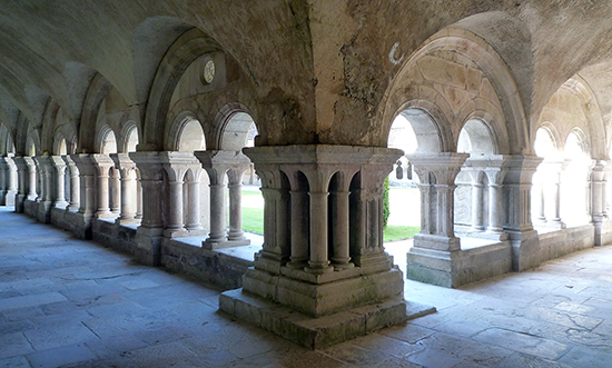 The cloister is an external covered walkway edged with archways. The design of the arches and column capitals is simplistic.