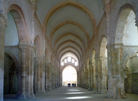 The aisles can be seen on either side of the nave. The nave's ceiling is arched and supported by stone.