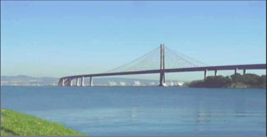 Fotografía a color del puente de Oakland Bay tomada desde la orilla de la bahía.