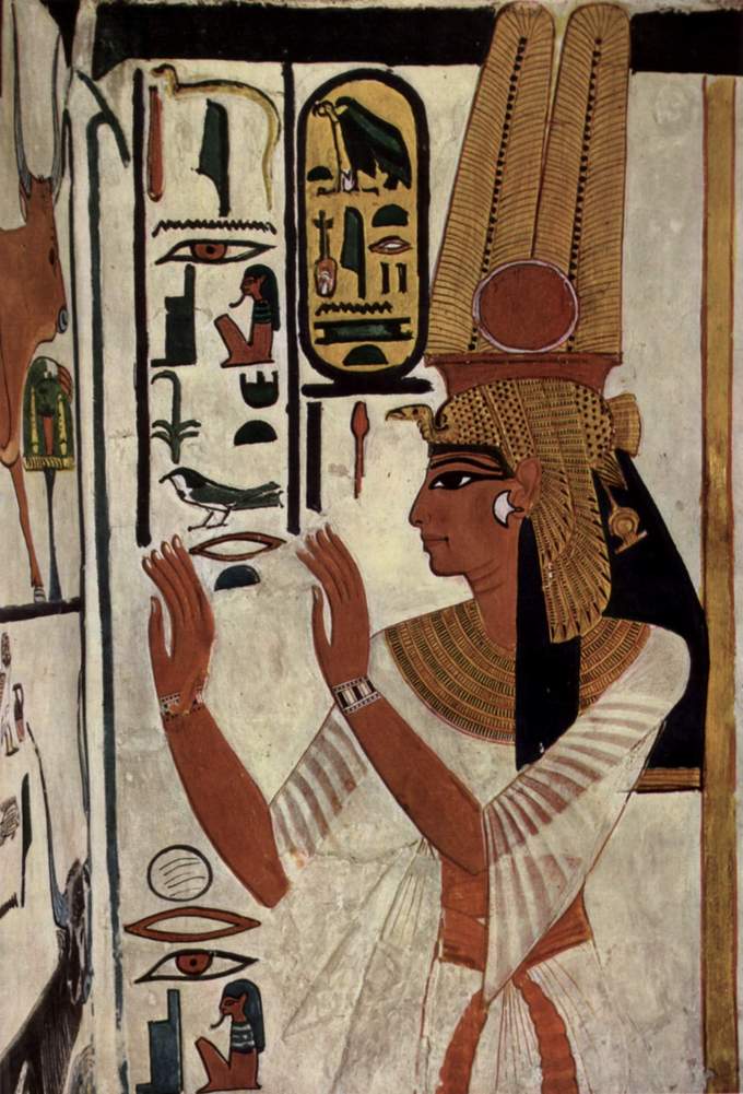 Wall painting depicts Nefertari. Her face is in profile view and she wears a tall elaborate gold hair covering. Her body is in frontal view. Her arms are raised in front of her.