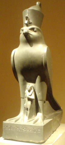 Sculpture depicts the pharaoh in miniature standing between the legs of a life-sized falcon.