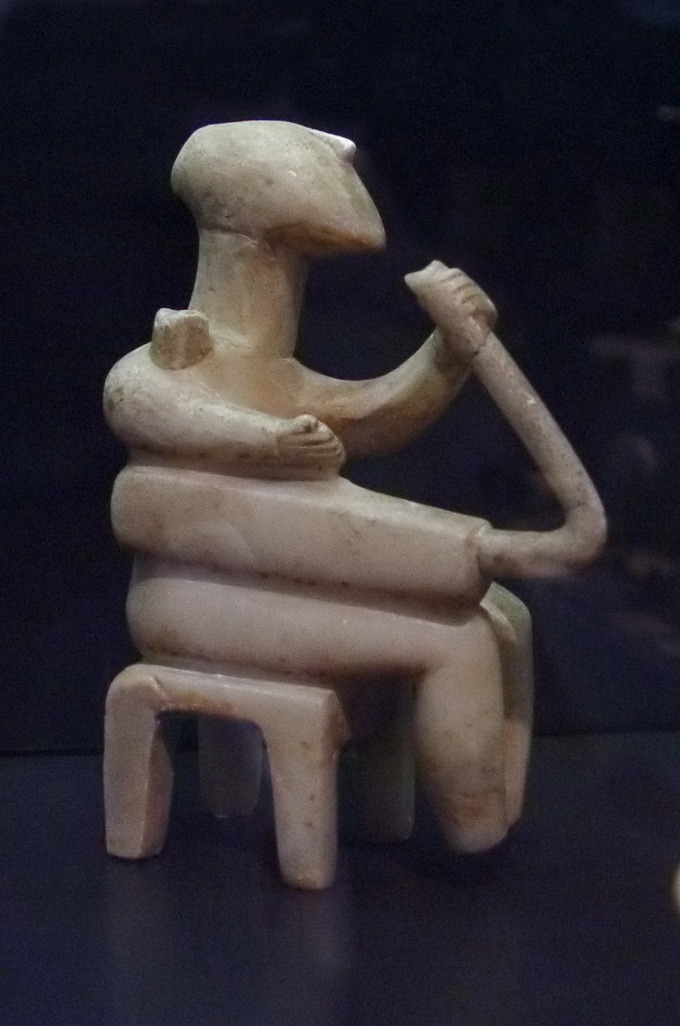 This is a color photograph of a Cycladic male figure playing the harp. It is made of marble and comes from Santorini, Greece, circa 2500 BCE.