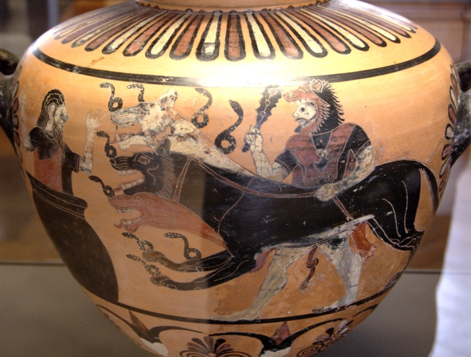 This is a photo of a pot painted with a scene of Hercules bringing Cerberus to Eurystheus. Cerberus is depicted as a black hound-like monster (a hydra) with multiple heads.