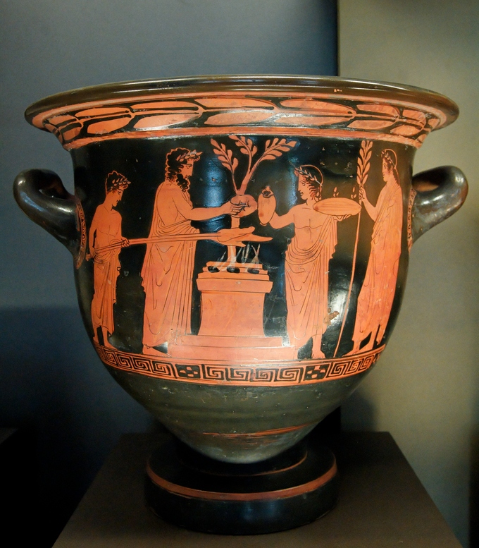 This is a photo of a krater with depiction of a scene of a sacrifice. Greeks dressed in togas and leaf crowns present a small animal to the gods.