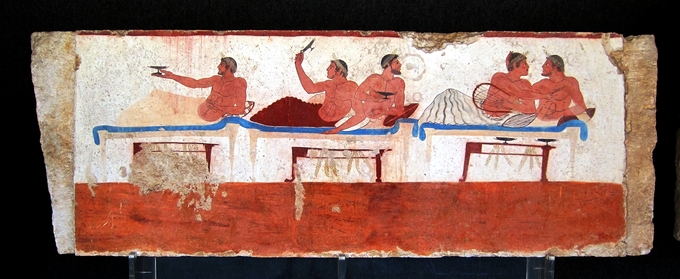 This symposium-scene fresco depicts five individuals on the couches on each wall, there is a single man on the left couch and the other two couches are occupied by two people. Each of the figures is covered to the waist, and they are all crowned.