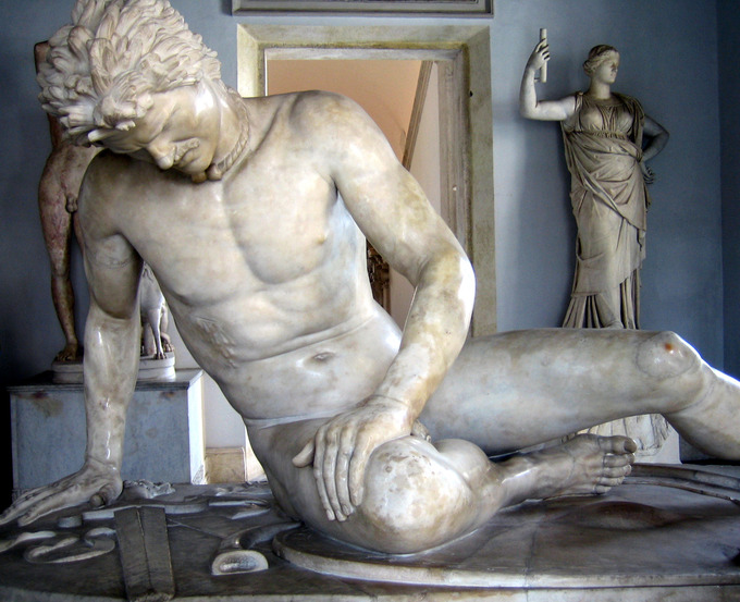 This is a photo of the Dying Gaul. The white marble statue depicts a wounded, slumping male figure. A bleeding sword puncture is visible in his lower right chest.