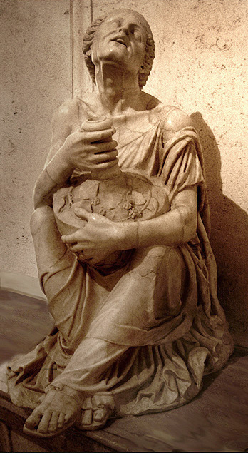 This is a photo of the Drunken Old Woman. The sculpture depicts an old woman squatting on the ground holding a container in her lap.