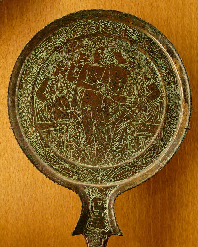 This is a photo of an Etruscan bronze mirror with an engraving of the Judgment of Paris, which depicts a contest between the three most beautiful goddesses of Olympos--Aphrodite, Hera and Athena. They compete for a golden apple.