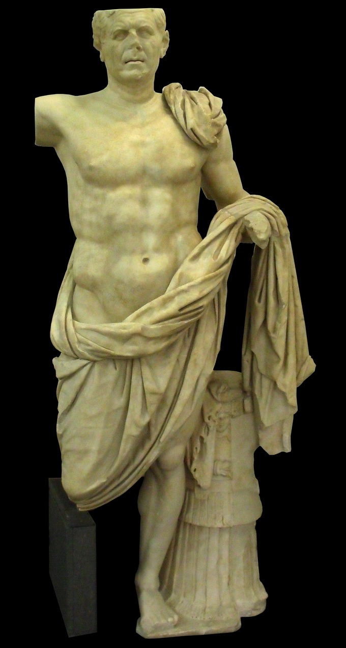 This photo shows the statue, Portrait of a Roman General. He wears a toga that shows his bare chest and idealized abdominal muscles. He stands with one leg bent and hidden under the toga.