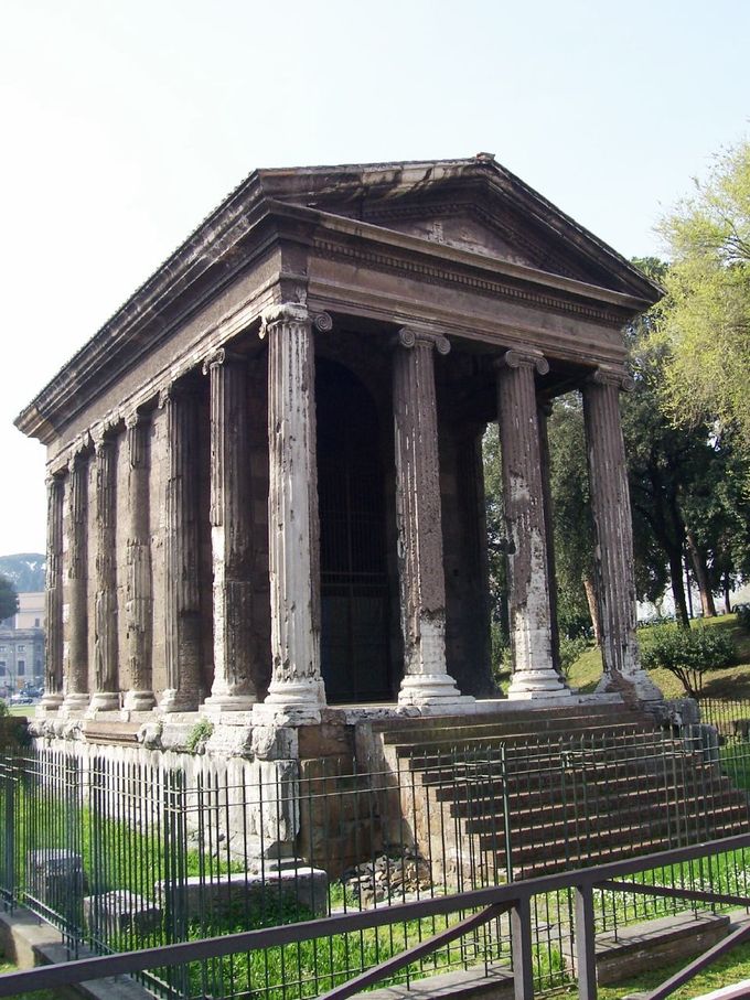 This photo shows the Temple of Portunus. It is a rectangular building raised on a high podium reached by a flight of steps. It has a portico of four Ionic columns across and two columns deep.
