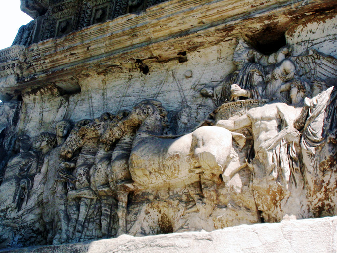 This photo shows a relief from the Arch of Titus. Titus rides in a chariot pulled by several horses.